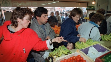 DDR-Besucher interessieren sich am 10.11.1989 in einem Geschäft in Herleshausen für Obst und Gemüse. | Bild: picture-alliance/dpa