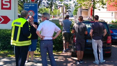 Passanten und Einsatzkräfte der Polizei stehen am 23.06.2016 in Viernheim (Hessen) in der Nähe eines Kinos, in dem sich ein bewaffneter Mann verschanzt haben soll. | Bild: dpa/Einsatzreport Südhessen