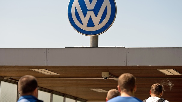 Mehrere Männer gehen am 19.08.2016 vor Schichtbeginn im Volkswagenwerk in Wolfsburg auf ein Werkstor zu. | Bild: picture-alliance/dpa