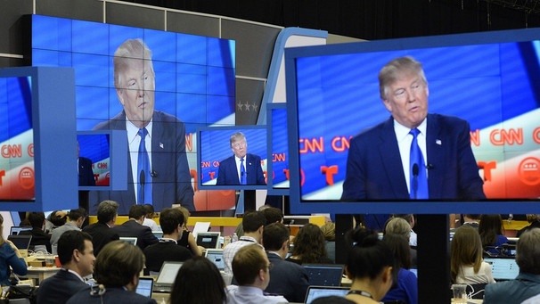 Menschen sehen einer Rede von Donald Trump zu, die im amerikanischen Fernsehsender CNN übertragen wird.  | Bild: dpa/Larry W. Smith 