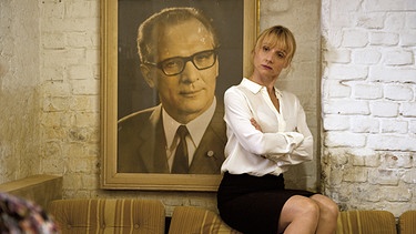 Dr. Eckart (Christina Große) kommt dem Bild von Honecker gefährlich nahe. | Bild: BR/NDR/Novafilm GmbH/WDR/Alva Nowak