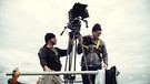 Kameramann Willy Dettmeyer hoch oben auf einem Dach (rechts) und ein Teammitglied. | Bild: BR X-Filme/Hagen Keller