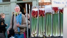 Ein Mann steht vor einem Geschäft mit Blumen, neben ihm stehen Amaryllis als Schnittblumen zum Verkauf. | Bild: mauritius images / Elena Rostunova / Alamy / Alamy Stock Photos