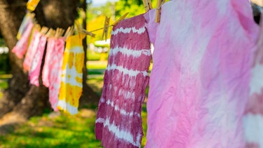 Gebatikte Tücher hängen zum Trocknen auf einer Wäscheleine | Bild: mauritius images