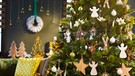 Mit Holzsternen und weißen Engeln geschmückter Weihnachtsbaum steht in einer Wohnung | Bild: mauritius images