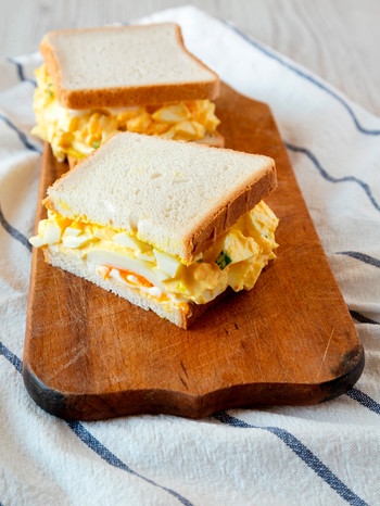 Auf einem Holzbrett liegen Sandwiches mit Ei | Bild: mauritius-images