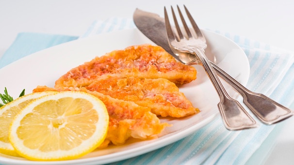Auf einem Teller liegen panierte Fischfilets mit Zitrone | Bild: mauritius images / Alamy / HelmaSpona