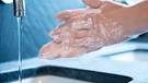 Eingeseifte Hände über einem Waschbecken | Bild: mauritius images