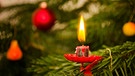 Eine echte Kerze an einem Weihnachtsbaum, fast heruntergebrannt. | Bild: mauritius images