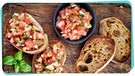 Brotstücke mit Tomaten liegen auf einem Holzbrett | Bild: colourbox.com
