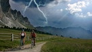 Zwei Mountainbikerinnen in Gewittersituation am Peitlerkofel in den Dolomiten. | Bild: mauritius images / Joerg Reuther / imageBROKER