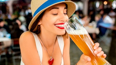 Eine junge Frau trinkt ein alkoholfreies Weißbier im Biergarten | Bild: mauritius images / RossHelen editorial / Alamy / Alamy Stock Photos