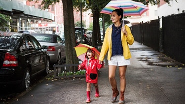 Glückliche Frau mit kleiner Tochter gehen im Regen spazieren | Bild: mauritius images / Cavan Images