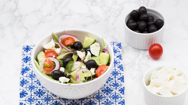 Griechischer Salat in Schalen auf blau-weißen Kacheln. | Bild: mauritius-images