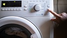 Eine Person bedient eine Waschmaschine. | Bild: BR/Johanna Schlüter