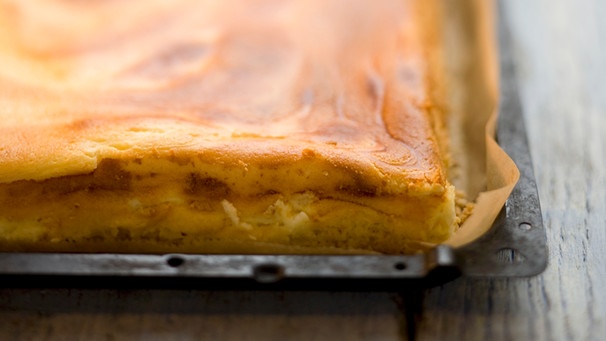 Auf einem Backblech liegt ein fertig gebackener Käsekuchen. | Bild: mauritius images / foodcollection