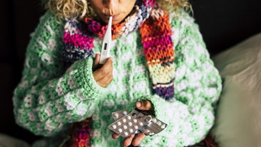 Kranke Frau mit Fiebertermometer und Tabnetten | Bild: mauritius-images