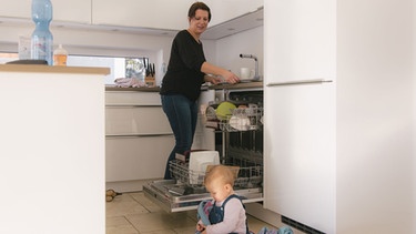 Junge Frau räumt Spülmaschine ein. | Bild: BR