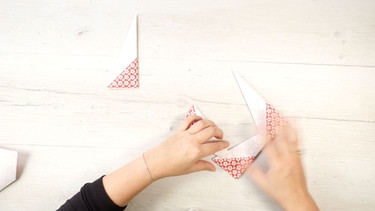 Hände zeigen, wie aus Origami-Papier ein Rahmen gefaltet wird. | Bild: Bogdan Kramliczek