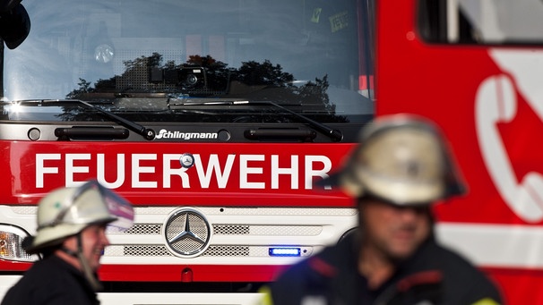 Symbolbild: die Front eines Feuerwehrautos, davor Feuerwehrleute  | Bild: picture-alliance/dpa