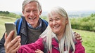 Ein älterer Mann und eine ältere Frau sind beim Wandern unterwegs. Sie machen ein Selfie mit dem Smartphone. | Bild: colourbox.com