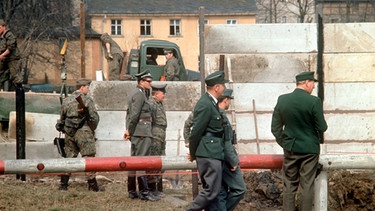 Westdeutsche Grenzbeamte beobachten 1966 ostzonale Truppeneinheiten bei der Errichtung einer Sperrmauer in dem von der innerdeutschen Grenze geteilten fränkischen Ort Mödlareuth. | Bild: picture-alliance/dpa