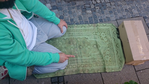 Ein Muslim betet an einem Infostand  | Bild: BR / Joseph Röhmel