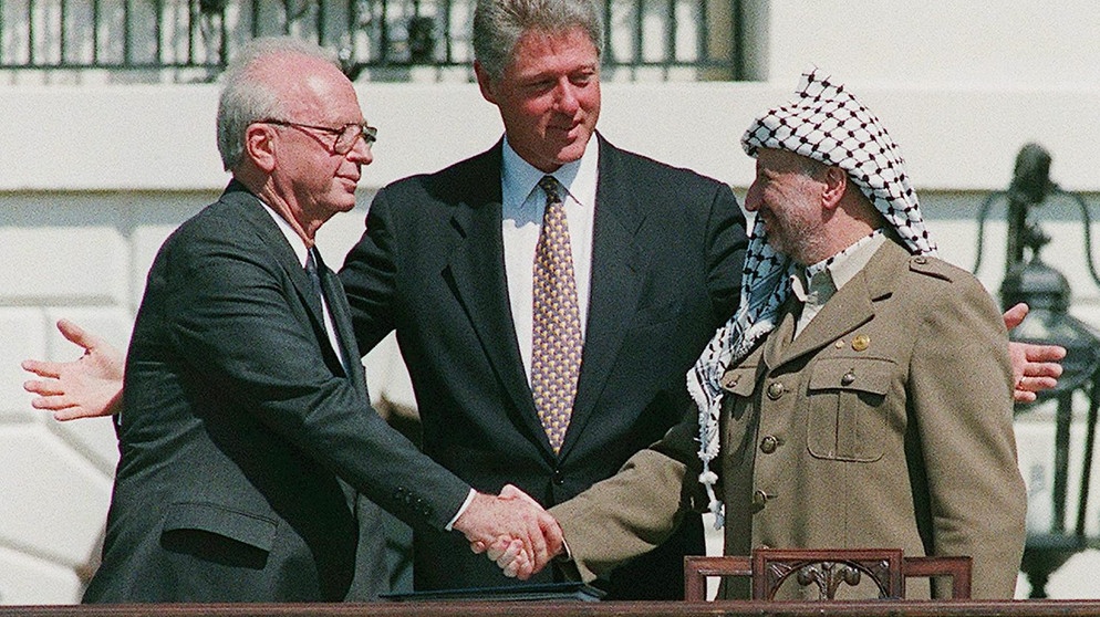 ARCHIV - 13.09.1993, USA, Washington: Izchak Rabin (l), damaliger Ministerpräsident von Israel, und Jassir Arafat (r), damaliger Vorsitzender der Palästinensischen Befreiungsorganisation PLO, geben sich im Beisein von Bill Clinton, damaliger US-Präsident, die Hand. Es ist ein Bild, das wie kein anderes die großen Hoffnungen auf einen Frieden zwischen Israel und den Palästinensern symbolisiert. | Bild: dpa-Bildfunk/Avi Ohayon/Israeli Government Pr