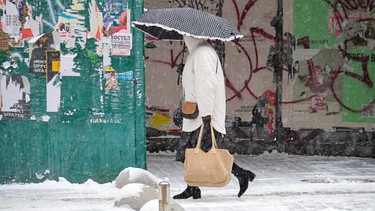 27.11.2023, Ukraine, Kiew: Eine Frau geht bei Schneefall unter einem Regenschirm durch die Stadt. Große Teile der ukrainischen Schwarzmeerküste wurden am Sonntag von einem plötzlichen Wintereinbruch erfasst und lahmgelegt | Bild: dpa-Bildfunk/---