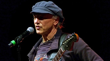 Lutz Kerschowski auf der Bühne mit Gitarre und Microfon | Bild: Ron Mertiny