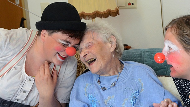 Im Altenheim St. Gertrud in Leipzig (Sachsen) hat die 101-jährige Heimbewohnerin Gertrud Köhler viel Spaß beim Besuch der beiden Clowns Sophie Hanses-Ketteler (r) und Maritta Brauer. | Bild: picture-alliance/dpa