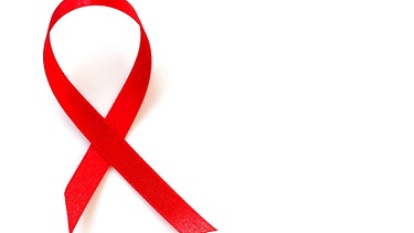 Rote Aidsschleife auf weißem Grund. | Bild: picture-alliance/dpa