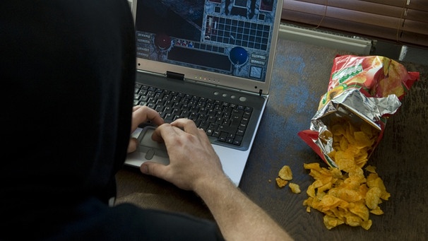 Jugendlicher sitzt vor Computerspiel, daneben eine Tüte Chips | Bild: picture-alliance/dpa