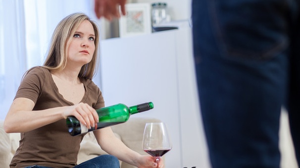 Junge Frau gießt sich schlechten Gewissens Rotwein ein. Ihr Freund stellt sie zur Rede. | Bild: picture-alliance/dpa