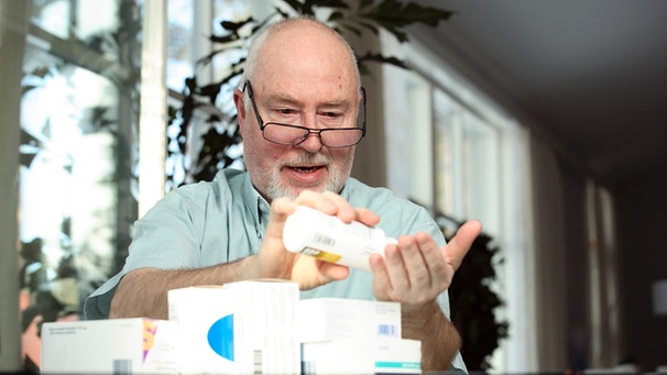 Mann bei der Einnahme von Tabletten mit zahlreichen Medikamentenschachtel auf dem Tisch | Bild: colourbox.com