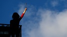 Frau hält rote Nelke hoch. | Bild: picture alliance / NurPhoto / Pedro Fiuza