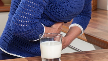 Frau hält sich Bauch, davor Glas mit Milch | Bild: colourbox.com