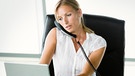 Symbolbild: Frau an einem Schreibtisch telefoniert und schreibt gleichzeitig an einem Laptop | Bild: colourbox.com
