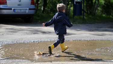 Kind läuft durch eine Pfütze | Bild: picture-alliance/dpa