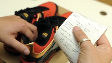 Kundenrechte - Was Ihnen als Kunde bei Garantie und Gewährleistung zusteht: Kunde hält Kassenbon und Schuhe in der Hand | Bild: picture-alliance/dpa