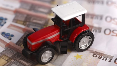 Symbolbild Traktormodell auf Euro-Geldnoten: Bauern in finanzieller Not | Bild: picture-alliance/dpa