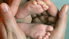 Hände halten Babyfüße | Bild: picture-alliance/dpa