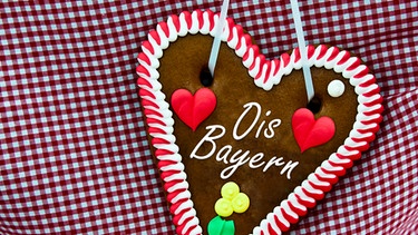 Lebkuchenherz mit aufschrift "Ois Bayern" auf rot-weiß-karriertem Tuch | Bild: colourbox.com, BR; Montage: BR
