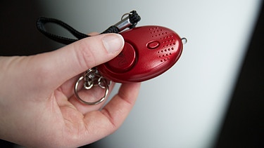 Eine Hand mit einem Taschenalarm | Bild: picture-alliance/dpa