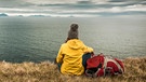 Frau mit Rucksack sitzt vor einem See in Island | Bild: picture alliance / Zoonar | Erik Reis - IKOstudio