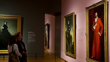 Zwei Frauen blicken auf das Gemälde von John Singer Sargent: "Dr. Pozzi at Home", während einer Ausstellung im Rijksmuseum in Amsterdam,  2018 | Bild: picture alliance/AP Photo | Peter Dejong