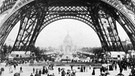 Ausstellungsbesucher wandeln unter dem Eiffelturm, die Sensation der Weltausstellung in Paris 1889 | Bild: picture-alliance/dpa