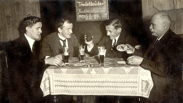 Vier Männer in einer Kneipe in Berlin um 1925 beim Würfelspiel und Biergenuss. Auf einer Holztafel steht "Trudelbrüder Nackten und Grauen §11." Der Paragraf 11 bedeutet in den Biergesetzen: "Es wird fortgesoffen". | Bild: picture-alliance/dpa