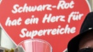 Im Hintergrund ein Schild "Schwarz Rot hat ein Herz für Superreiche"- Demonstranten halten am 30.06.2016 vor dem Bundesrat in Berlin Einweggläser in den Händen und lassen sich Sekt einschütten. Die Organisation Attac hatte zu einer Protestaktion gegen das geplante Erbschaftssteuer-Gesetz aufgerufen.  | Bild: picture-alliance/dpa