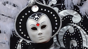 Mensch mit schwarz-weißer Maske, Kopf- und Federschmuck | Bild: picture-alliance/dpa